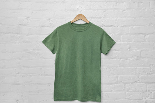 Green T-shirt on hanger against light brick wall background