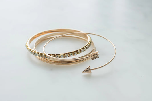 Rose gold bangles with clear stones arranged in a row on a light surface